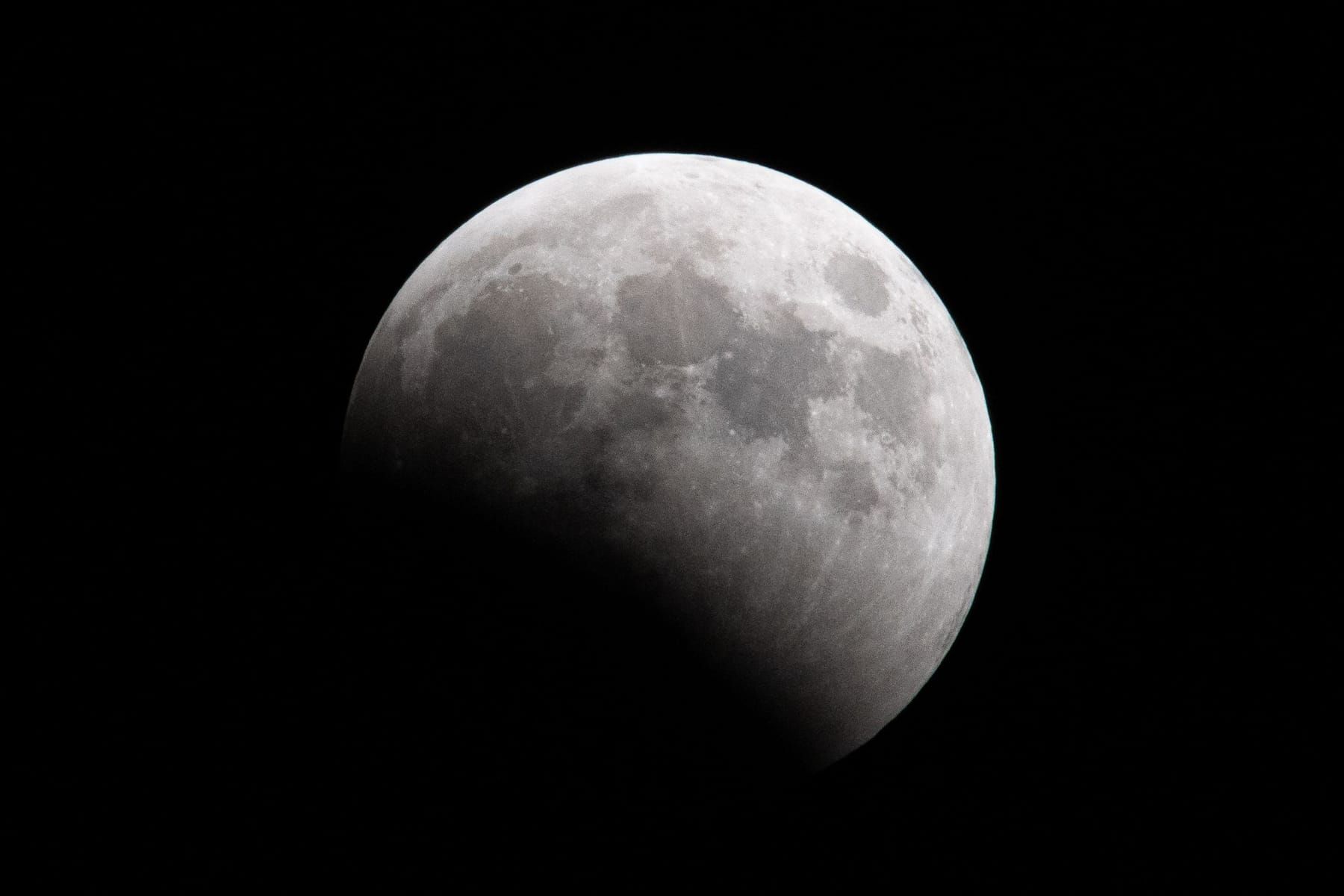 Moon with its lower left part darkened by the curved edge of Earth's shadow